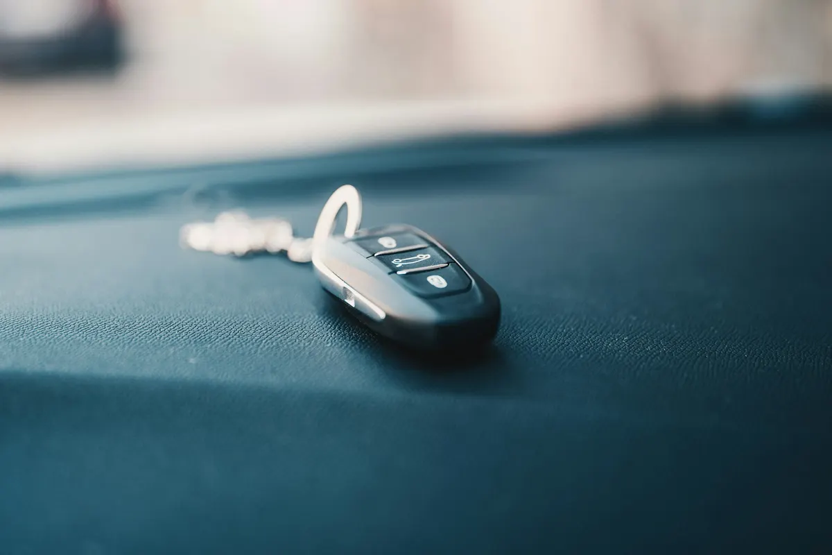 A car key fob resting on the roof of a dark car