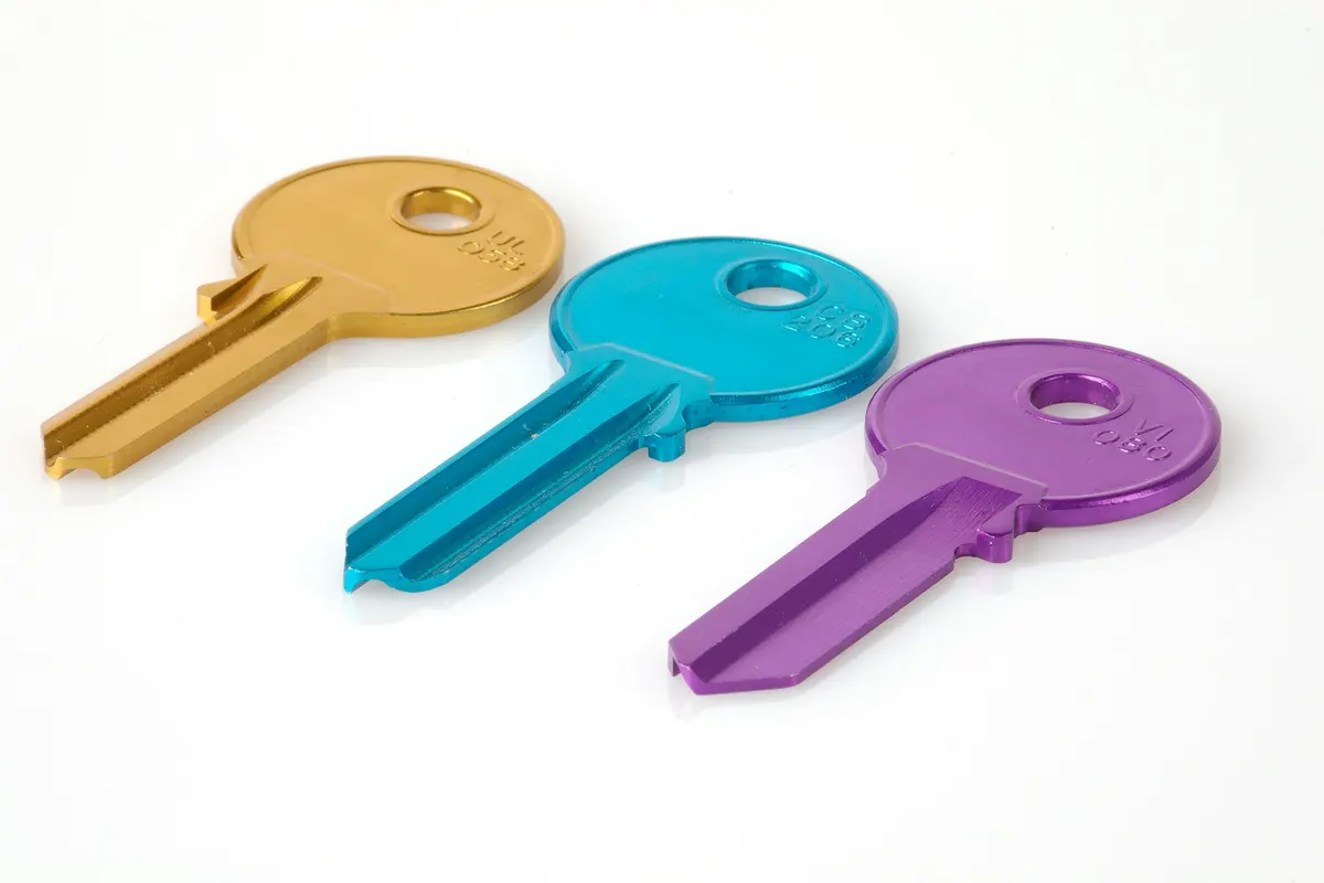 Three uncut colored key blanks on a white surface